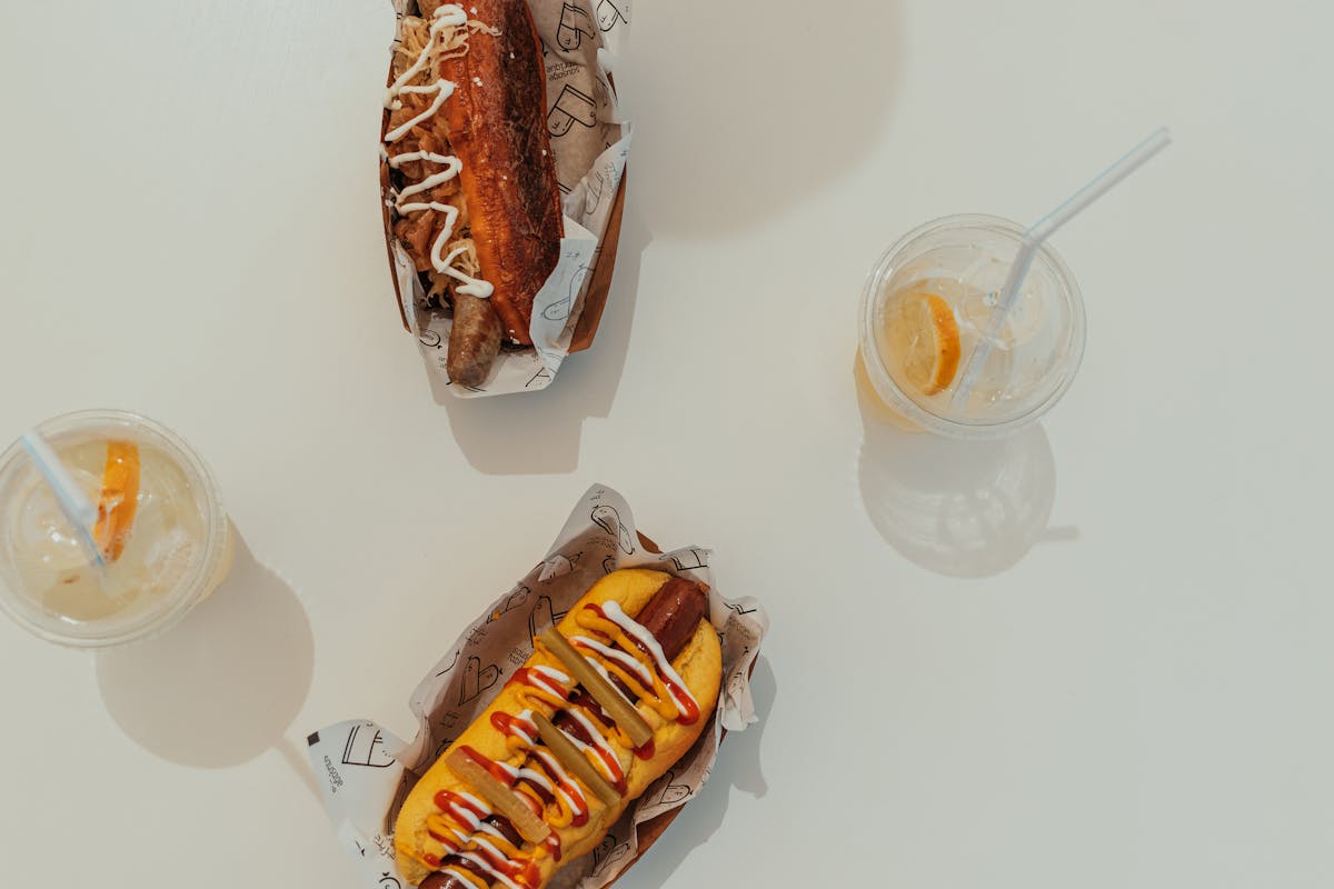 Two loaded hot dogs with toppings and condiments served with drinks
