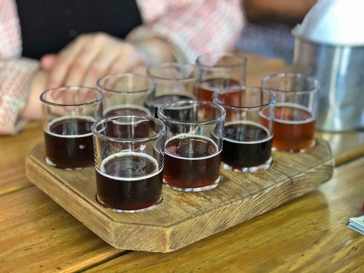 A variety of craft beers served on a wooden tray for tasting