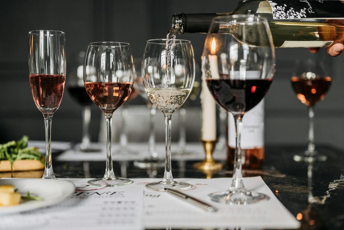 Wine tasting setup with several glasses of wine being poured on an elegant surface
