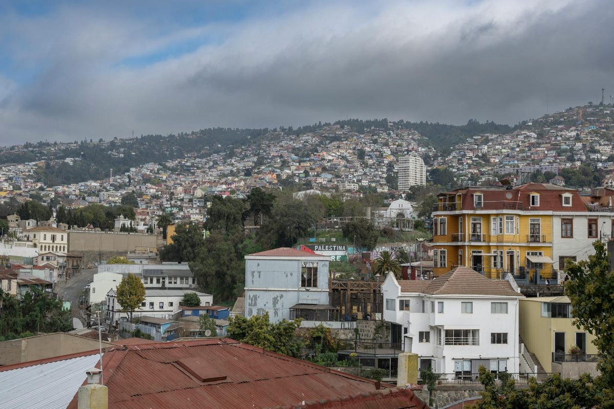 View of vibrant hillside houses in ValparaÃso, Chile, under cloudy skies.